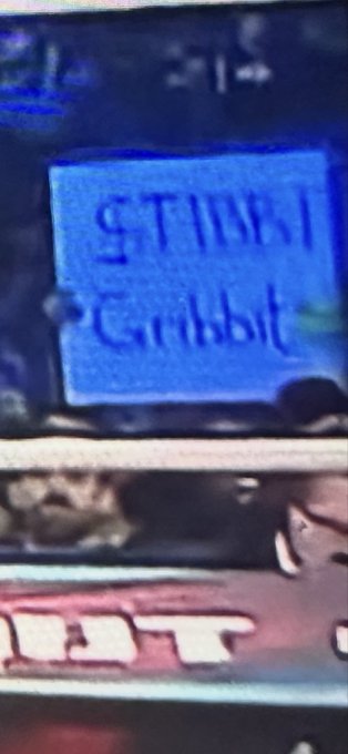 A grainy, low-resolution photo showing what appears to be a blue card or sign with text that reads 'STUBI' and 'Grabbit' in stylized lettering, with partial text '1B3T' visible below.