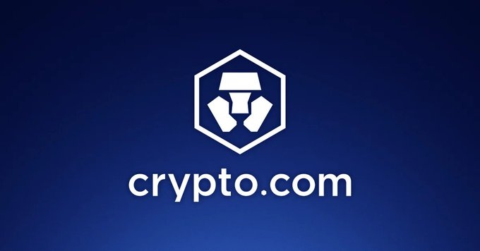The image displays the white Crypto.com logo, featuring a hexagonal emblem with a stylized geometric design, centered above the brand name "crypto.com" on a deep blue background. This branding directly ties to the post's announcement that Crypto.com is expanding into tokenised stock derivatives, highlighting the platform's pivot toward blending cryptocurrency trading with traditional stock market exposure.