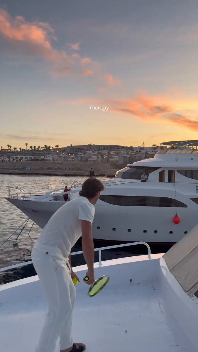 The image features a man holding a tennis racket, standing next to a boat that has "You and bro" written on its side. The scene suggests that they are preparing for a game of tennis or possibly just enjoying some leisure time together on the water. The photo also includes text that reads "You and bro in few years having your therapy session at Monaco on a yacht because you guys never gave up." This could be an indication that the man is determined to maintain his physical fitness, even as he ages, by engaging in activities like tennis with his friend or loved one.