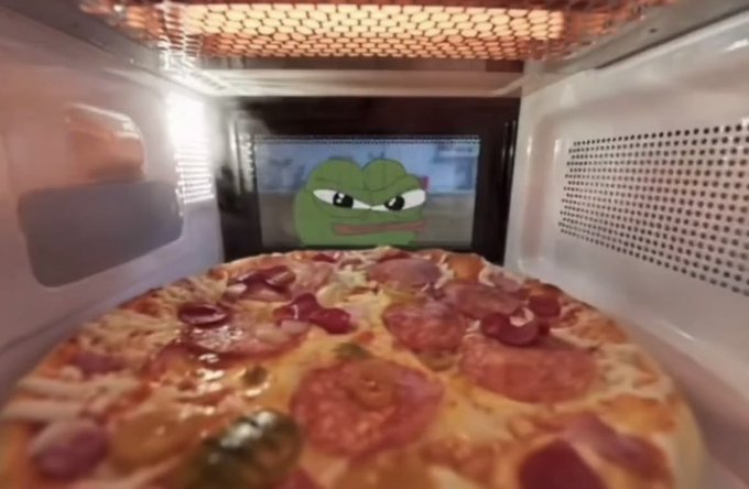 A pepperoni pizza is cooking in an oven, with a Pepe the Frog sticker visible on the oven's interior window.