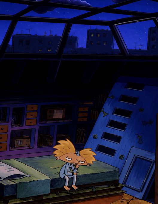 An animated cartoon scene showing a tired-looking character with spiky orange hair sitting on a bed in a dimly lit, blue-toned bedroom with a slanted ceiling.