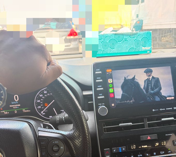 A driver's hand grips the steering wheel of a car displaying 0 km/h on the dashboard, while a video on the center console shows a man in a cap beside a horse, suggesting a moment of pause or reflection during the user's crypto journey from early Web3 losses to recovery.

Visible text includes "0 km/h," "94° D," "1165 RPM," "LO," and "YouTube" on the infotainment screen.
