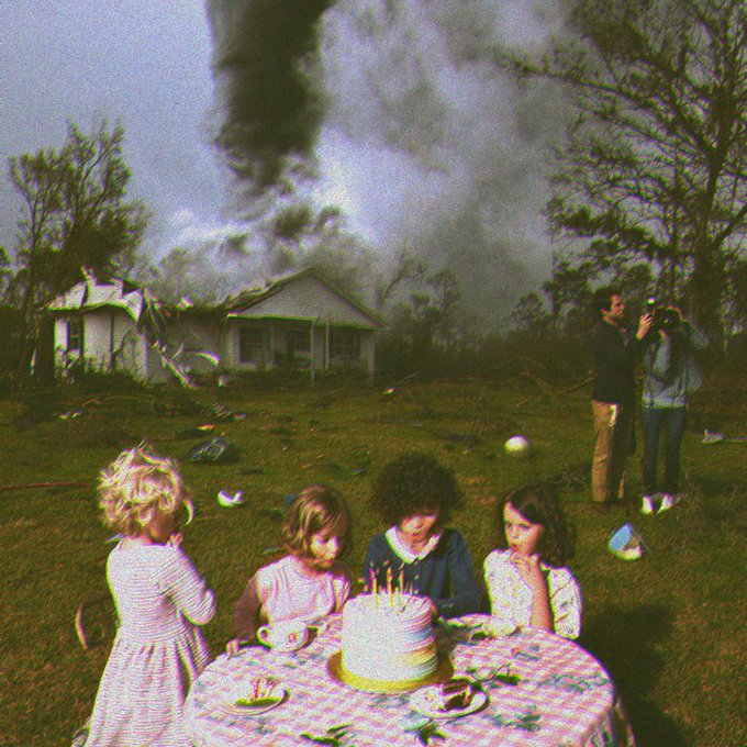 A surreal, dreamlike image showing children having a birthday party at a table with a cake in a grassy yard while a massive tornado rips through houses in the background and a photographer captures the scene.
