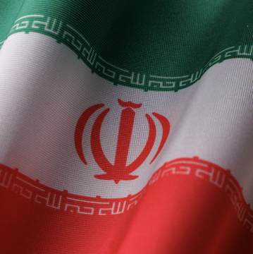 The national flag of Iran waves prominently, symbolizing the country at the center of US prosecutors' efforts to seize $61 million in cryptocurrency tied to black-market oil sales allegedly laundered through Binance by two Chinese companies to Iran and its proxies.
