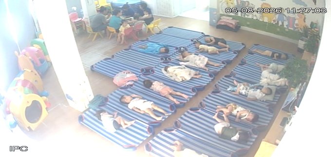 Surveillance camera footage dated '05-08-2024 11:27:08' showing children sleeping on blue-striped mats in what appears to be a daycare or preschool setting.