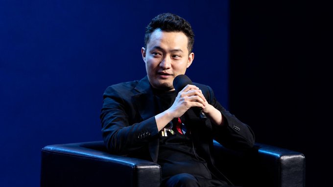 A man in a black suit speaks into a microphone while seated on stage at Bitcoin Asia in Hong Kong, with his name "SUN YUCHEN" visible on his badge. The image relates to the post by showing the speaker, @sunyuchentron, discussing how Bitcoin is emerging as a global macro asset and stablecoins' growing role in mainstream finance, with TRON building infrastructure for digital asset circulation.