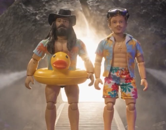 Two action figures dressed in Hawaiian vacation attire, including swim trunks, floral shirts, and sunglasses, stand side by side with one holding a yellow rubber duck pool float.