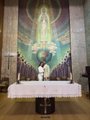 A small image showing what appears to be an altar or display with a figure in front of a colorful, ornate backdrop.