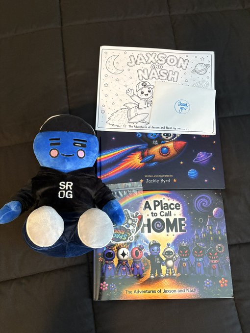 A plush toy wearing a 'SR OG' shirt sits next to two personalized children's books titled 'JAXSON AND NASH: The Adventures of Jaxson and Nash' and 'A Place to Call HOME', along with a coloring page and a 'thank you' note.