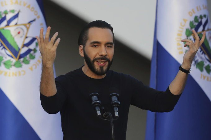 Nayib Bukele, President of El Salvador, gestures while speaking at a podium flanked by Salvadoran flags bearing the national seal ("República de El Salvador"). The image ties to the post's announcement about El Salvador adopting blockchain-based remittance services, reflecting the country's pioneering role in embracing crypto and stablecoin infrastructure for its citizens.