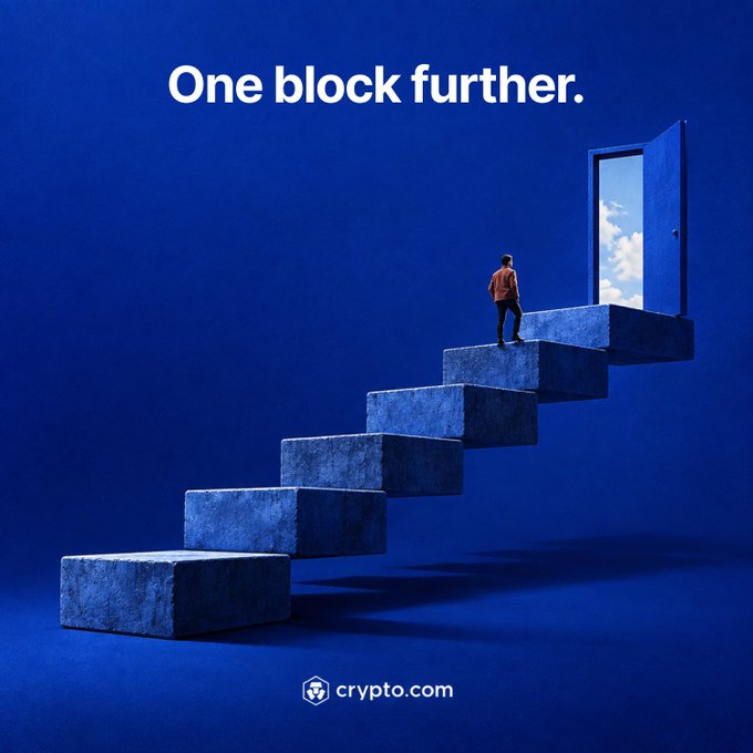 A person in an orange jacket climbs a staircase of large stone blocks toward an open door revealing a bright sky, with the headline "One block further." and the crypto.com logo beneath. The visual reinforces the post's message about consistent, incremental progress as the key to unlocking new opportunities.