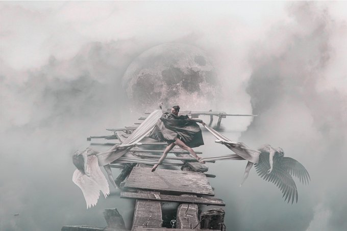 A surreal digital artwork depicting a figure with large angel wings standing on a fragmented, floating structure surrounded by clouds, with a massive moon in the background.