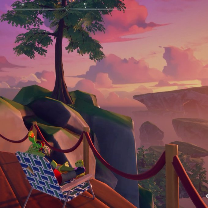 A stylized video game scene featuring a frog-like character wearing a crown relaxing in a striped beach chair on a wooden cliffside platform at sunset, with a red velvet rope barrier and a compass showing NE/E at the top.