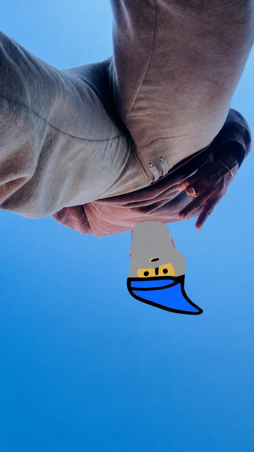 Upside-down photograph of two hands clasped in a suit against a blue sky, with a cartoon blue-capped gnome/character drawn floating below them.