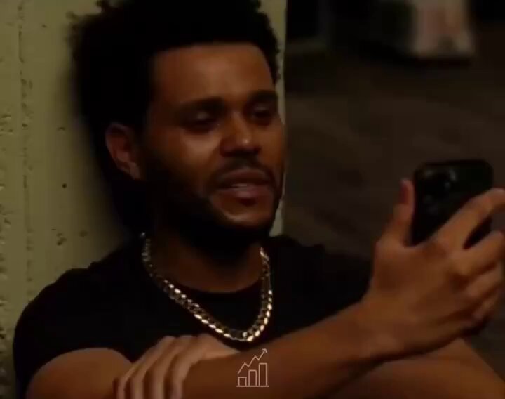The image features a man sitting down, holding a cell phone up to his face as if he's taking a selfie or looking at something interesting on the screen. The background of the photo shows a wall with a poster hanging on it that says " megaeth farmers after opening their wallet". This phrase is likely a reference to the popular song " megaeth farmers" by the band Radiohead, which became a hit in the late 1990s and early 2000s. The image seems to be related to this song or something similar, possibly as part of a discussion about music or pop culture trends at that time.