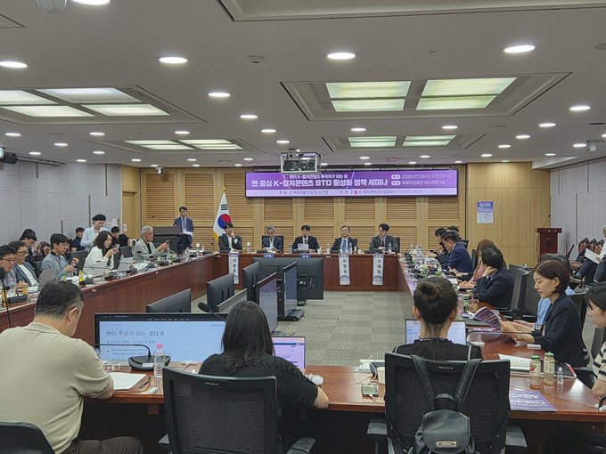 A formal Korean government or committee meeting taking place in a large conference room, with attendees seated at long tables and a Korean flag displayed prominently, with a banner mentioning a public hearing on the Budget Policy Office budget for 2025.