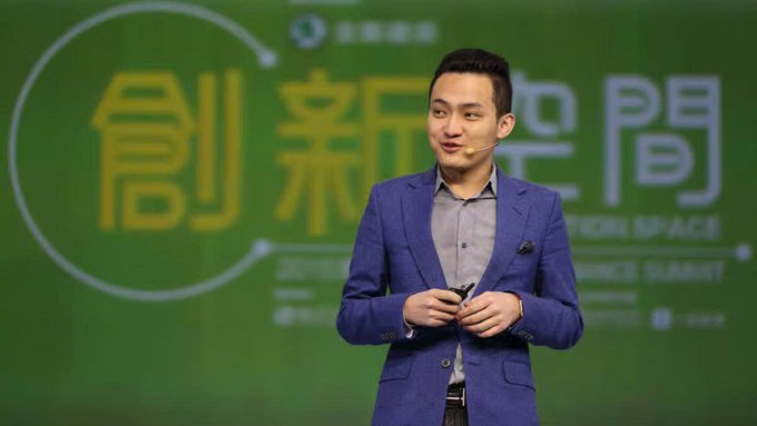 An Asian man in a blue blazer speaks on stage at a 'Eastern Space' conference, with Chinese characters displayed on the green screen behind him.