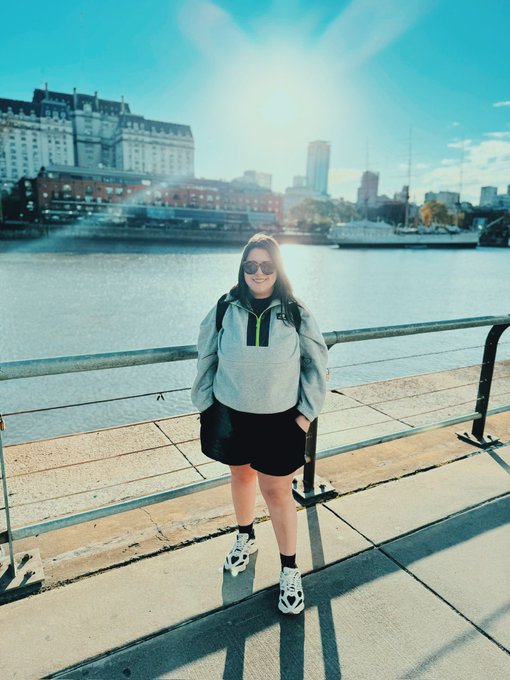 Ana poses on a sunny waterfront promenade, with a city skyline and boats visible behind her, as she reintroduces herself beyond her "CRIPTOLAWYER" persona—sharing her Venezuelan roots, legal background, and pioneering work in Latin America's blockchain space.
