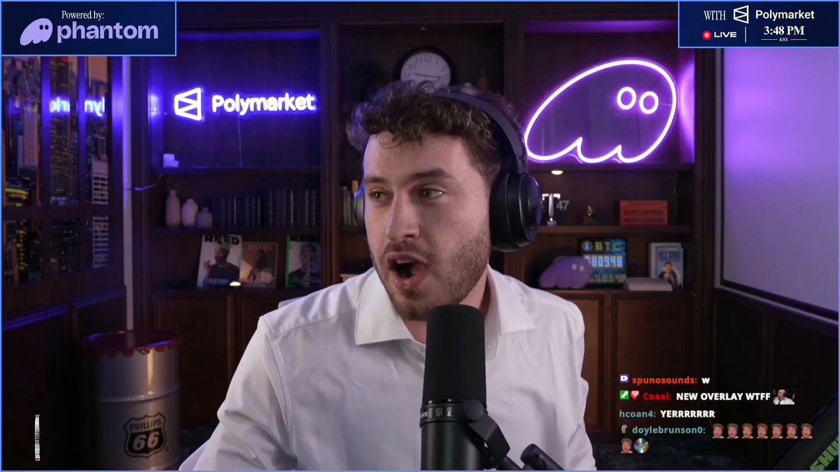 The image shows a man wearing headphones, standing at a microphone with his mouth open as if he's speaking into it. The background features a computer screen displaying a website called "tulipking" along with some text that reads "our stream today in 50 minutes ft. @tulipking 2:03 the new Counterparty 9:27 Saylor is exit liquidity now 13:21 Saylor is exit liquidity now 13:22 Saylor is exit liquidity now 13:23 Saylor is exit liquidity now 13:24 Saylor is exit liquidity now 13:25 Saylor is exit liquidity now 13:26 Saylor is exit liquidity now 13:27". The image also includes a beer mug and a clock, suggesting that the man might be taking a break from work or enjoying some leisure time.