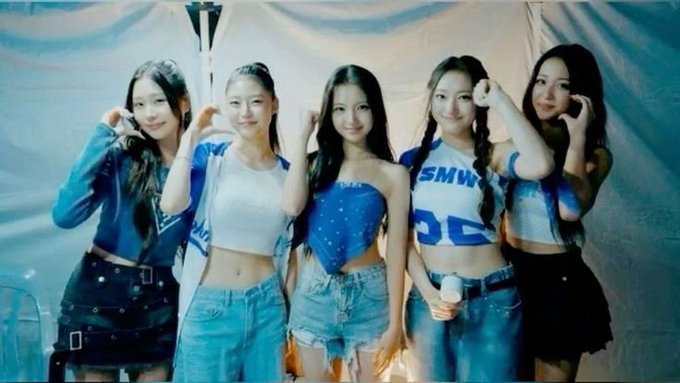 A photo of five young women in blue and white outfits posing together indoors, resembling K-pop idols.