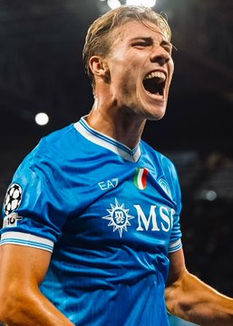 A jubilant soccer player in a blue Napoli kit with the EA7 and MSC sponsor logos, celebrating with an open-mouthed shout.
