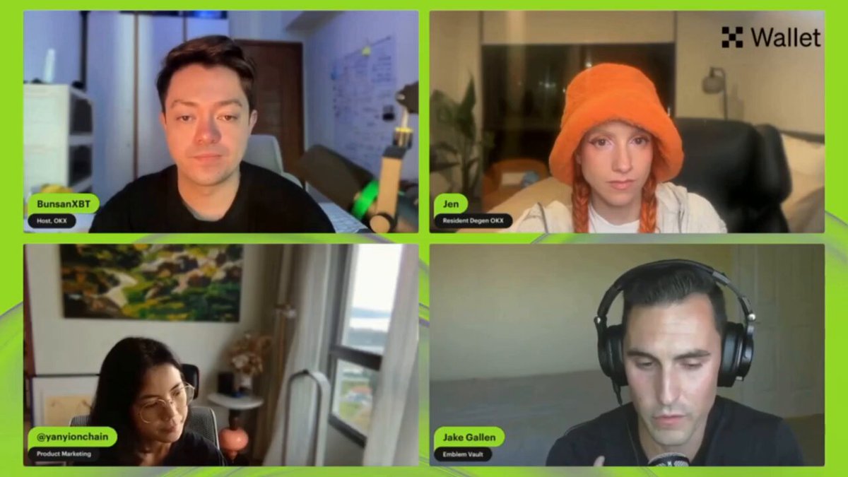 The image shows four people sitting at their desks during a video conference call. They are all wearing headphones and appear to be engaged in a conversation, possibly discussing something related to the @EmblemVault brand or wallet. The focus of the image is on the participants' faces as they interact with each other through the video conferencing platform.