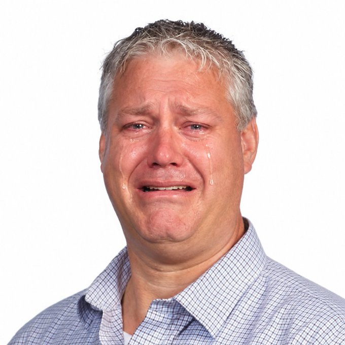 A close-up portrait of an older man with gray hair, wearing a blue checkered shirt, visibly crying with tears streaming down his face against a plain white background.