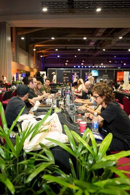 The image shows a group of people sitting around tables, working on laptops. There are at least ten people visible in the scene, with some seated closer together while others have more space between them. The tables are covered by black tablecloths, creating an organized and professional atmosphere for their work session. A potted plant is placed near one of the tables, adding a touch of greenery to the room.

The post on social media reads: "It's a beautiful day to build on @FlareNetworks". This message emphasizes the importance of collaboration and teamwork in today's digital age. The image captures this moment where people are coming together to work on their laptops, sharing ideas and knowledge with one another while enjoying each other's company.