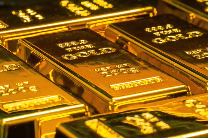 The image shows a close-up view of several gold bars stacked together, with some overlapping each other. The gold bars are shiny and reflect light, indicating their high value. The text in the image reads "If you had $50,000 to invest You can only choose Gold or Bitcoin!". This suggests that the gold bars could be used as a form of investment, either for purchasing gold directly from the seller or investing in Bitcoin if the post is related to Bitcoin investments.