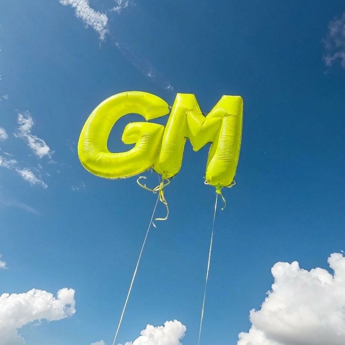Yellow letter-shaped balloons spelling 'GM' floating in a blue sky with white clouds.