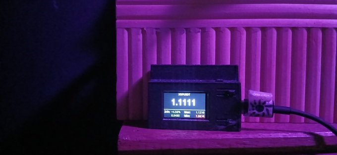 A small digital display device shows a reading of '1.1111' under purple/pink grow light conditions, with additional small data readouts below the main number.
