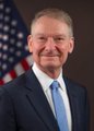 A man in a suit and tie stands before an American flag backdrop, blurred in motion as he moves across the frame. The image pairs with commentary praising SEC leadership's pro-crypto stance, suggesting their endorsement carries more credibility than political promises.