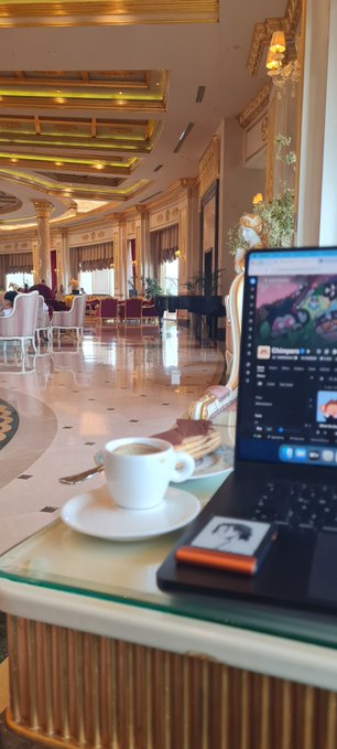 The image shows an open laptop computer sitting on top of a table, with a cup of coffee next to it. There are also cookies placed nearby. The background features a dining area with chairs and tables, suggesting that this scene takes place in a restaurant or similar establishment where people can enjoy their meals while working or browsing the internet. The post about Chimp is likely related to the content on the laptop screen, possibly discussing a popular social media platform or an interesting article shared by someone else.