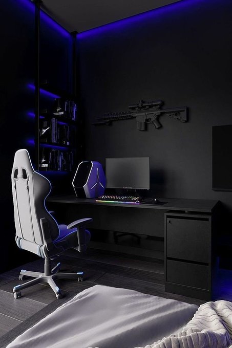 A modern gaming setup featuring a sleek white and blue gaming chair, a desk with a PC tower, monitor, and RGB keyboard, all set against a dark wall displaying a mounted rifle replica, illuminated by ambient blue LED lighting. The high-tech aesthetic reflects the engineering and tech-savvy background highlighted in the accompanying post about Bima's expertise as a Web3 growth strategist who bridges technical knowledge with marketing strategy.