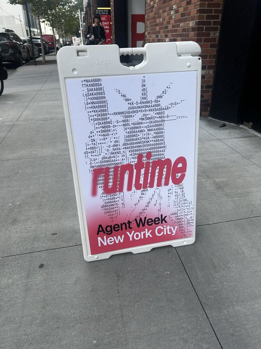A-frame sidewalk sign on a city street advertising 'runtime Agent Week New York City' with ASCII art forming a face pattern above the text.