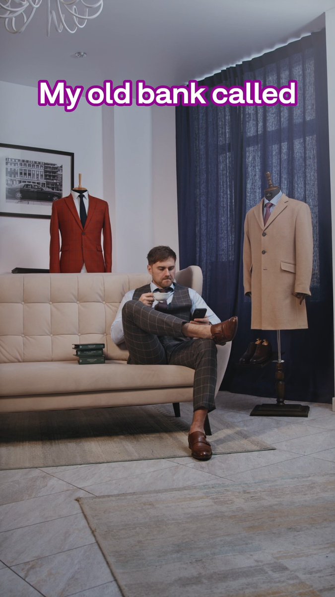 The image shows a well-dressed man in a checkered suit sitting on a cream tufted couch, holding a teacup and phone, with mannequins displaying a rust-colored suit and a camel overcoat flanking him. The text overlay reads "My old bank called," which paired with the post humorously contrasts his polished, attentive appearance with the dismissive attitude of letting his old bank call go to voicemail, in contrast to picking up for Skrill.