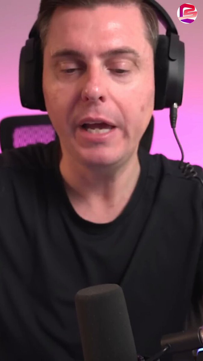 The image shows a man wearing headphones, possibly listening to music or participating in an online radio show. The man appears to be talking into a microphone while wearing a black shirt. There are two other people visible in the background of the image, but they do not seem to be directly involved with the main subject.