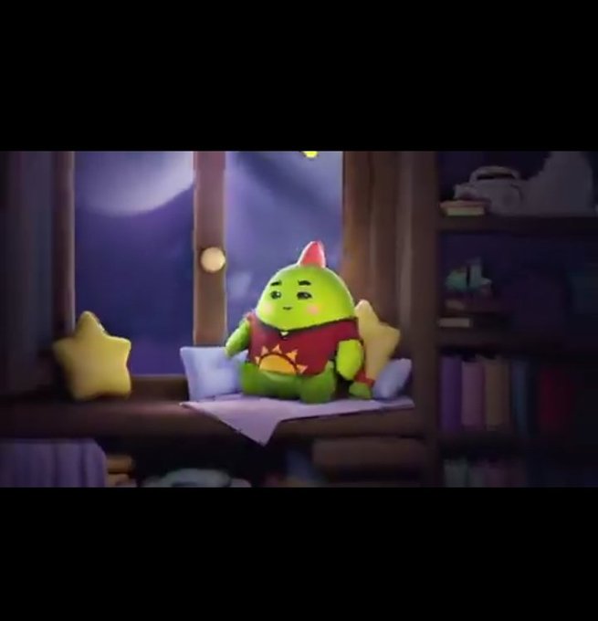 A green animated character with a pink party hat sits on a window seat with star-shaped pillows, looking out a window at night in a cozy room setting.