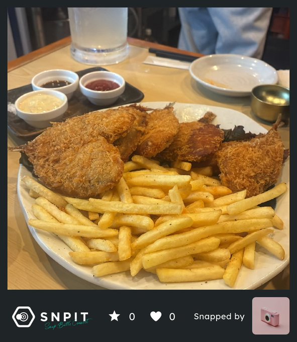 The image shows a plate of food consisting of fried chicken, french fries, and dipping sauce. The plate is placed on top of a dining table with various condiments available for use. The caption of the image includes the hashtag #SNPIT and a star icon, which could be related to the post or an event happening at the location where the photo was taken.