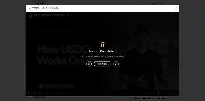The image shows a computer screen displaying an online learning platform called "How USDC Works Onchain". The screen has a green button that says "Lecture Completed!" at the top, indicating that the user has successfully completed their lecture. The background of the screen is black with white text and images related to the course content.