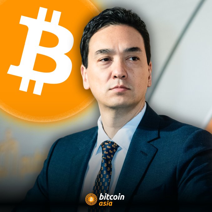 The image features a man dressed in a suit, standing against a white background with an orange circle above him that says "BITTECOIN ASIA" written in black letters. The man appears to be looking down at something or someone off-camera. The caption below the image reads "CEO of METAPLANET SIMON GEROVICH: “#Bitcoin tests patience before it rewards conviction.” KEEP HODLING".