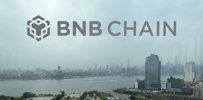 The BNB Chain logo with text 'BNB CHAIN' displayed over a misty city skyline along a waterfront.
