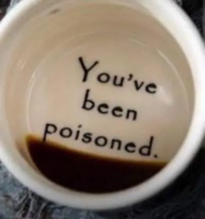The inside of a ceramic cup containing a small amount of dark liquid bears the printed message 'You've been poisoned.'