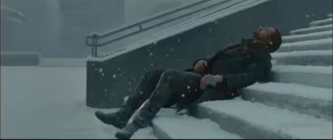 The image shows a man lying down on stairs, possibly after a fall or an accident. The scene appears to be set in a snowy environment with snowflakes falling around him. There are no other people visible in the image, which adds to the sense of solitude and isolation. The caption provided seems unrelated to the main subject matter of the image and does not provide any context about the market or its current state.