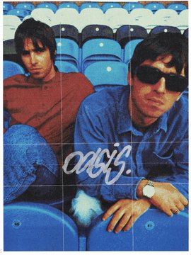 Two men sit in blue stadium seats, with the man in the foreground wearing dark sunglasses and a denim shirt, and the cursive text "oasis" written across the image—evoking the iconic Britpop band Oasis in a stadium setting.