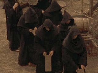 The image shows a group of people wearing black robes, standing close together with their hands clasped behind their backs. They appear to be part of a religious or spiritual community, as indicated by the text "crapdano community". The focus on this detail suggests that the image might be related to a discussion about the community's beliefs and practices, or it could simply be an artistic representation of the group in a particular setting.