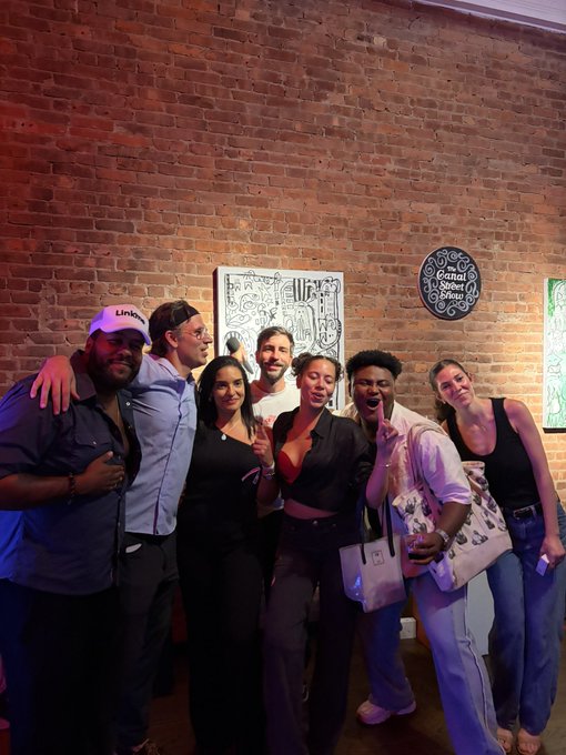 A group of people pose together inside a brick-walled venue, with a chalkboard sign reading 'Connect' and a 'Canal Social Hour' logo visible on the wall behind them.
