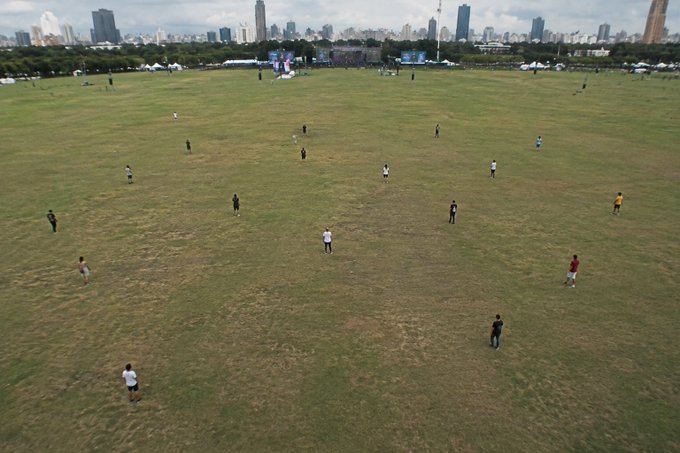 An aerial view shows a sprawling grassy field with scattered people, the empty expanse framed by distant city buildings and tents. The image humorously captures the "rare sight" of Centretown's open space being sparsely populated, illustrating the social media post's joke about how the area becomes deserted once morning arrives.