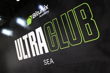 The image displays a promotional sign reading "Bitunix Academy" and "ULTRA CLUB SEA" in white and green lettering against a dark background with illuminated stadium-style lights. It relates to the post by visually representing the launch event of the first Bitunix Ultra Club in Southeast Asia (SEA), a VIP experience bringing together trading community members for golf, conversation, and rewards.