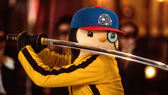 A cinematic image of the Duolingo owl mascot dressed in a yellow tracksuit and blue-and-red baseball cap, holding a katana sword in a fighting stance.